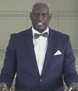 A person in a suit and bow tie standing at a podium
AI-generated content may be incorrect.